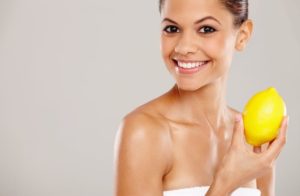 Vitamin C symbolisiert von junger Frau mit schöner Haut und Zitrone in Hand 