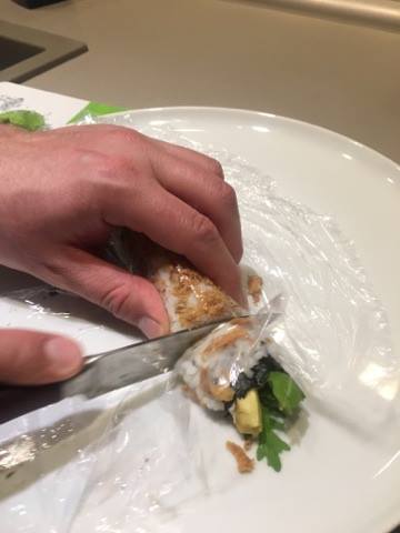 selbstgemachte Sushi Rolle wird mit Messer geschnitten