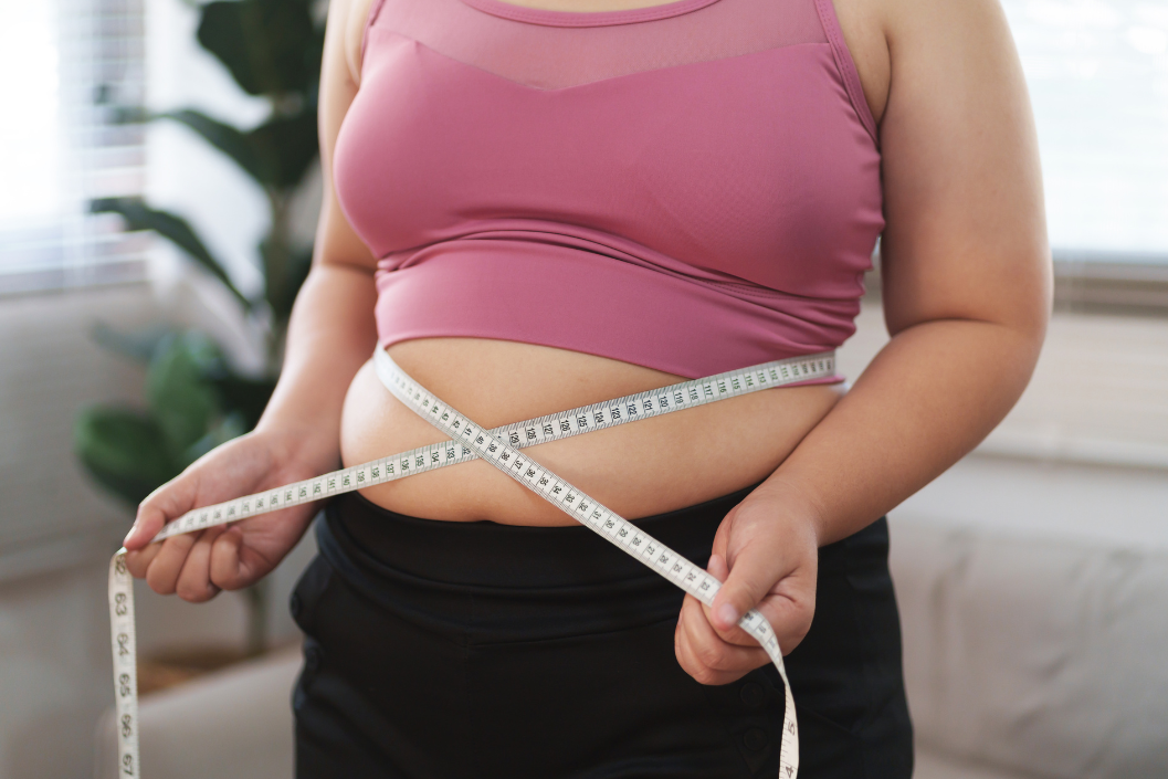 übergewichtige Frau mit Maßband möchte ihre Hüfte trainieren