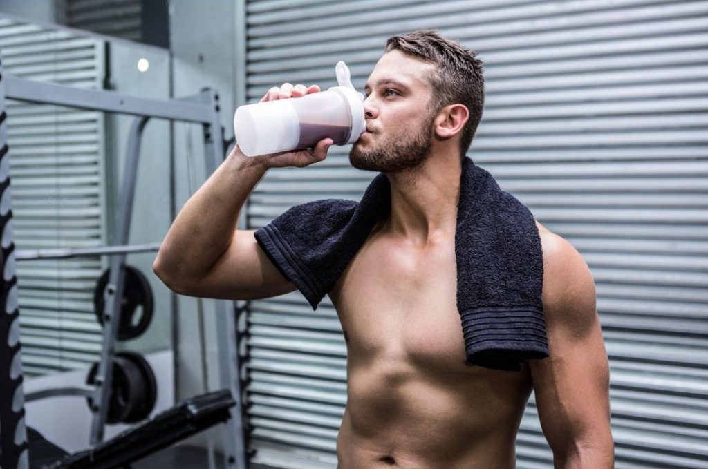 Sportler oberkörperfrei trinkt Shake zum Muskelaufbau