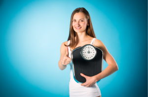 Welcher BMI ist normal - dargestellt von Frau mit Waage