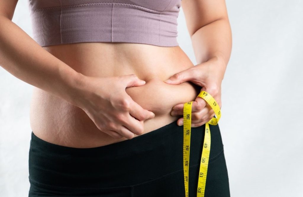 übergewichtige Frau misst Bauchumfang
