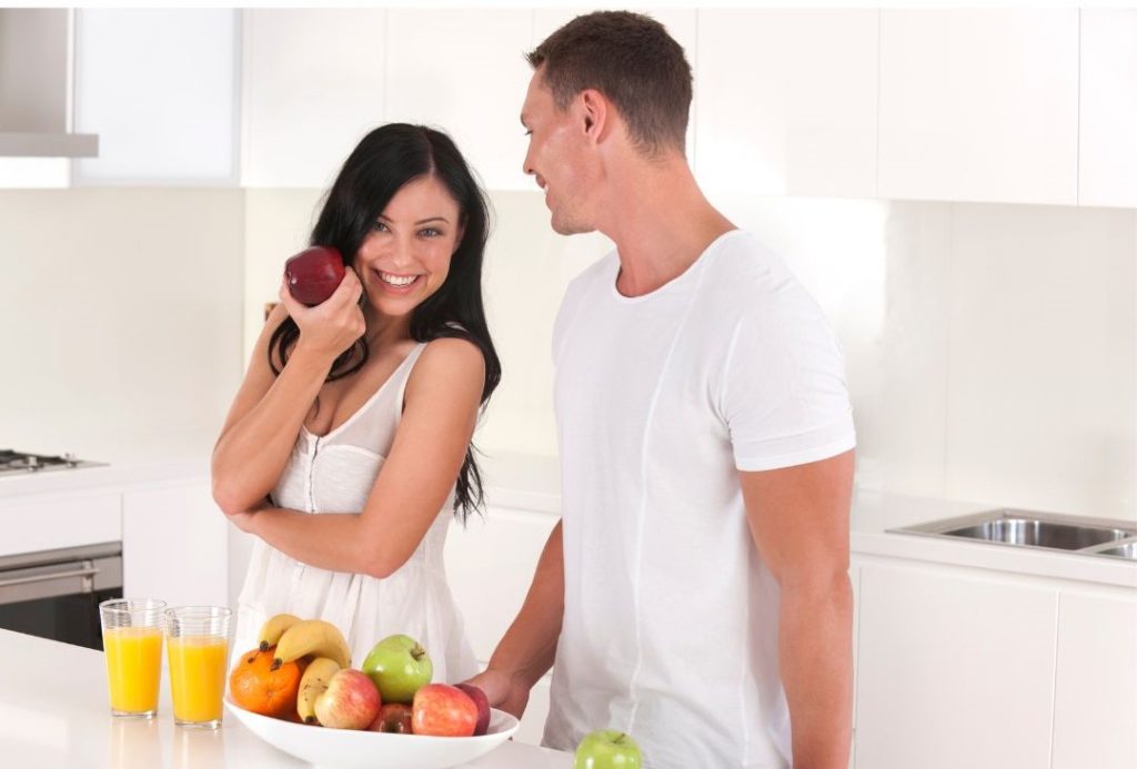 fittes Paar in Küche mit Obst symbolisisert Intervallfasten