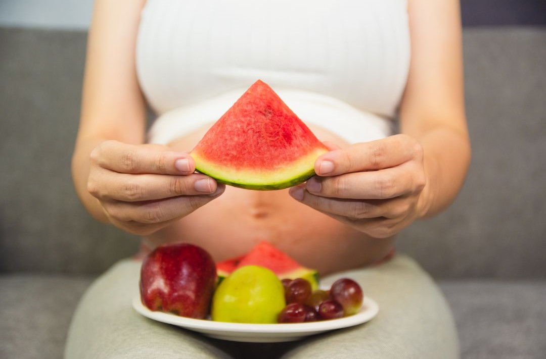 schwangere Frau isst Obst und sollte keine Low Carb Diät machen