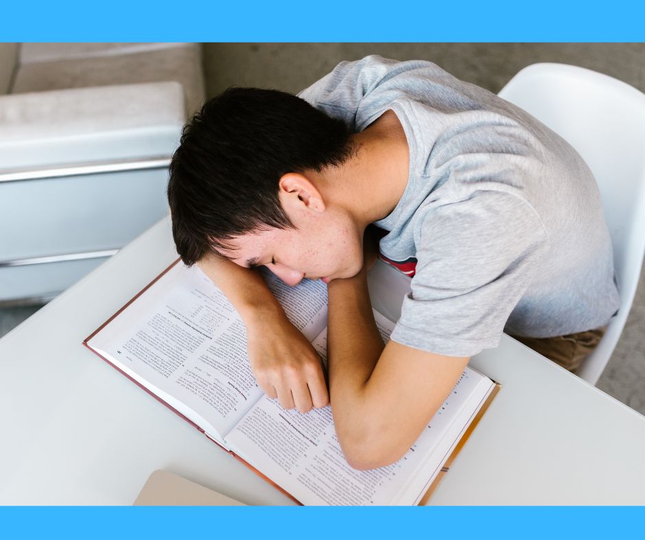 junger Mann schläft auf Büchern ein und symbolisiert damit die Erschöpfung durch Long Covid im Alltag