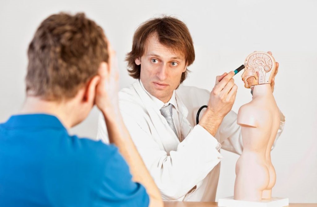 Patient mit Kopfschmerzen beim Arzt in Behandlung