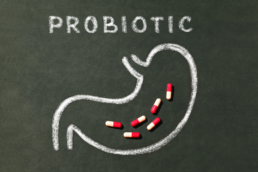 Probiotika Text mit Magen gemalt und Tabletten