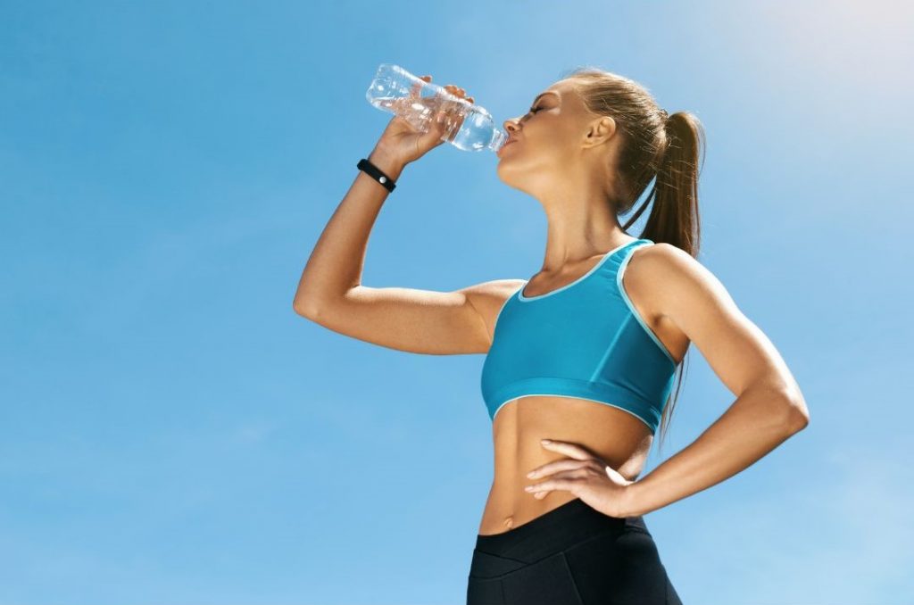 Schnell Abnehmen durch viel Wasser trinken, dargestellt von sportlicher Frau
