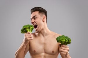 Muskelmann isst Brokkoli zum Abnehmen
