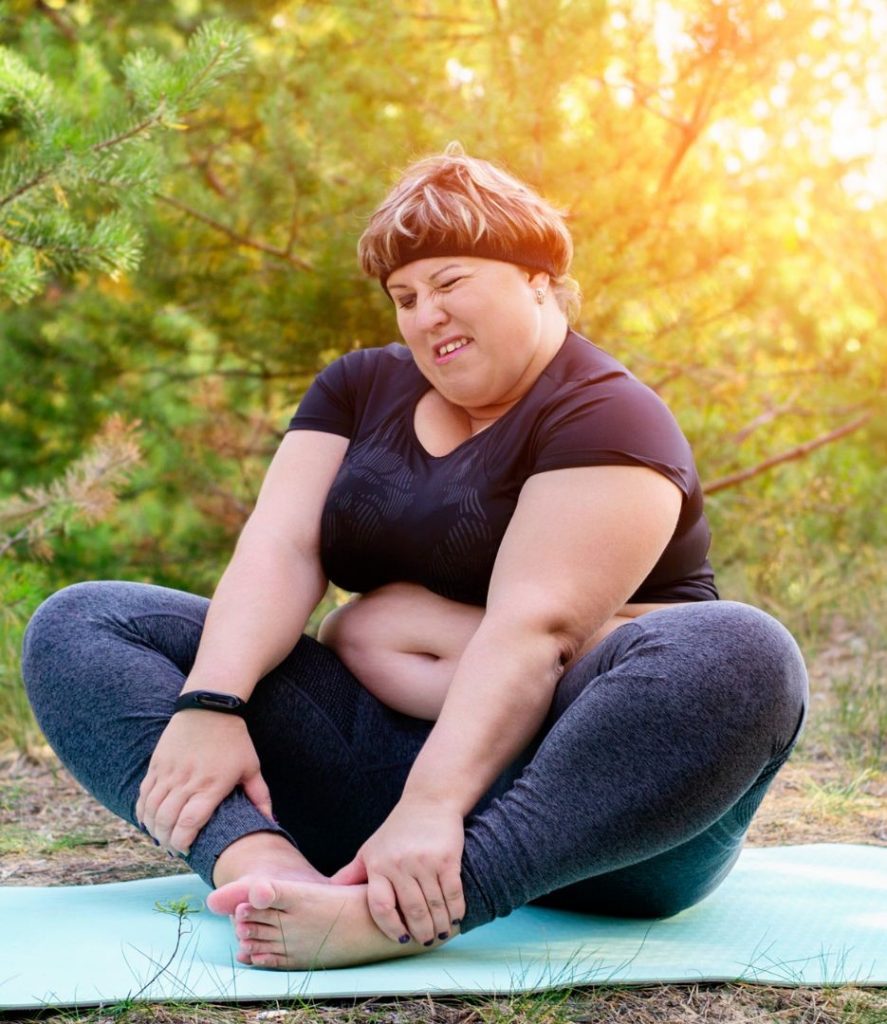 übergewichtige Frau symbolisiert Sport auf Yogamatte als besten Weg zum Abnehmen