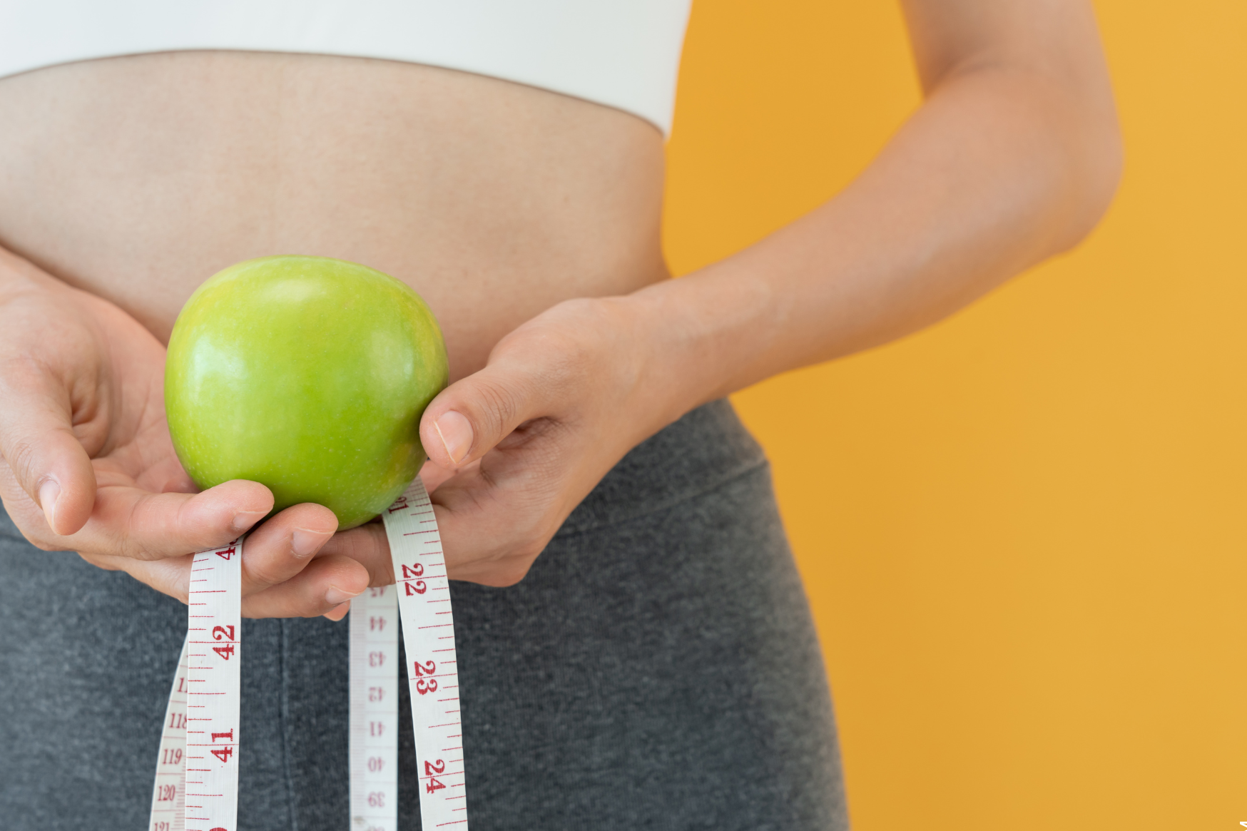 Abnehmen ohne Sport symbolisiert von Frau mit Apfel