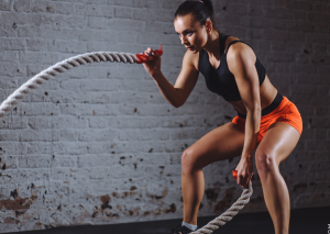 Strandfigur durch hartes Workout dargestellt von Frau mit Battle Rope