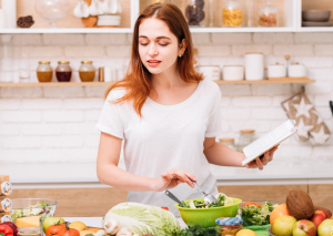 junge Frau kocht mit gesunden Zutaten symbolisch für Clean Eating