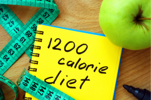 Kalorien zählen symbolisiert durch Apfe, Maßband und Tagebuch