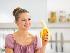 Banane essen hilft gegen Wassereinlagerungen im Sommer, dargestellt von Frau