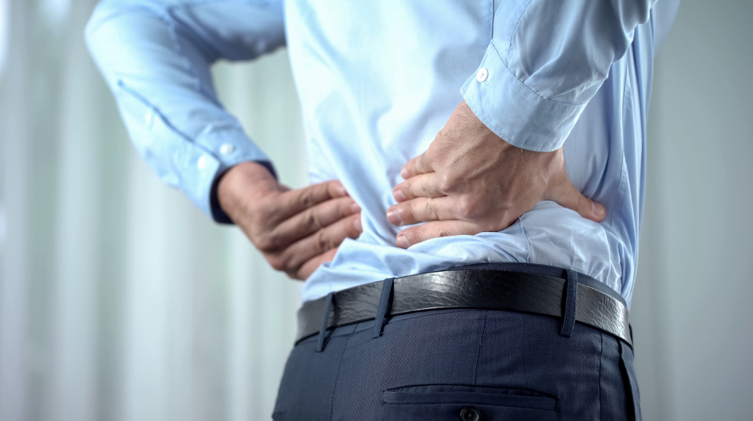 Bandscheibenvorfall symbolisiert von Mann im Anzug mit Rückenschmerzen