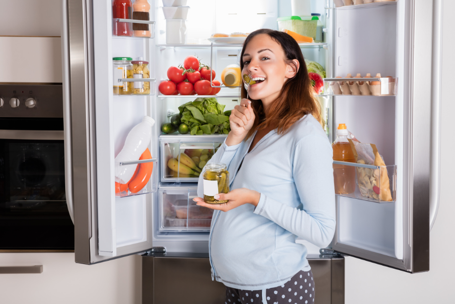 Ernährung in Schwangerschaft dargestellt von Schwangerer vor Kühlschrank