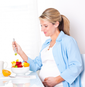 Ernährung in Schwangerschaft dargestellt von Schwangerer mit Obstteller