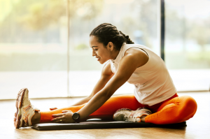 Trainingsplan zum Abnehmen beinhaltet auch Stretching, dargestellt von junger Frau