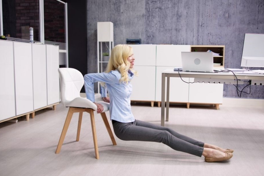 Krafttraining im Alltag dargestellt von Frau bei Dips im Büro